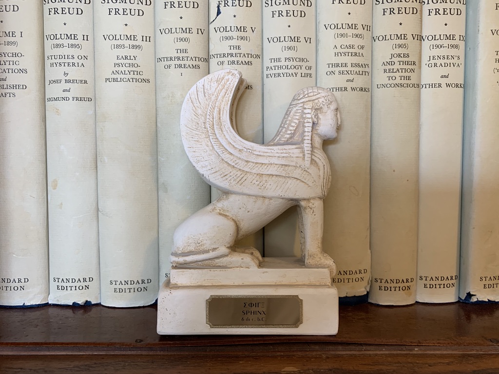 Sphinx sculpture in front of psychoanalytic books